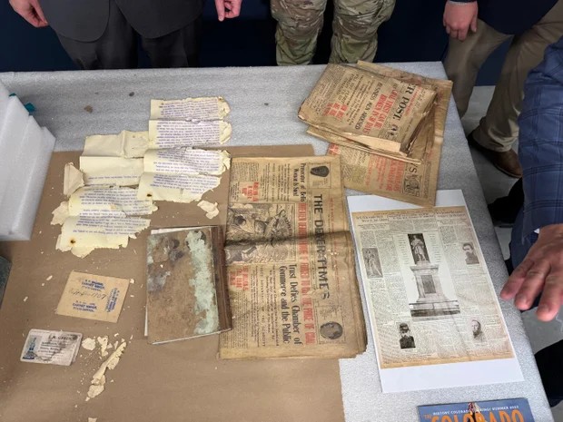 Photograph of the time capsule's contents. Notice the extremely damaged document in the upper left. That is the one that crumbled into confetti as the governor removed it. Also notice the book with black mold directly below it. Image from CBS News.